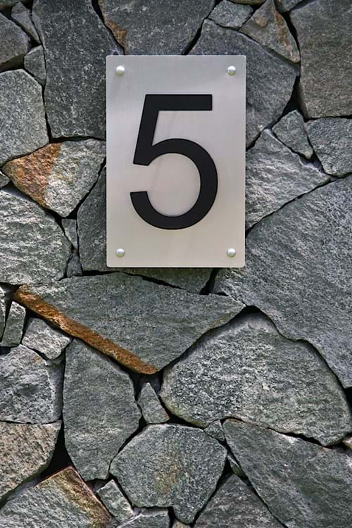 Porphyry stone clad wall with stainless steel numbering