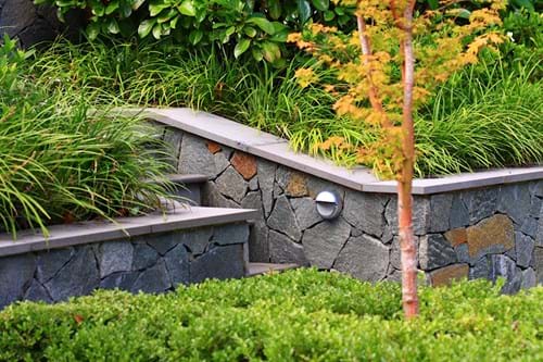 Porhyry stone cladding to low retaining walls with bluestone capping